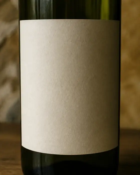 Gros plan sur une étiquette crème d’une bouteille de vin verte, avec la mention imprimée en petites capitales
