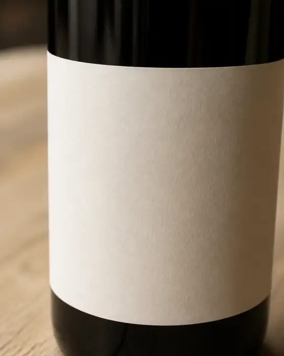 Gros plan sur l’étiquette d’une bouteille de vin où figure la mention d’appellation, posée sur une table de bois clair