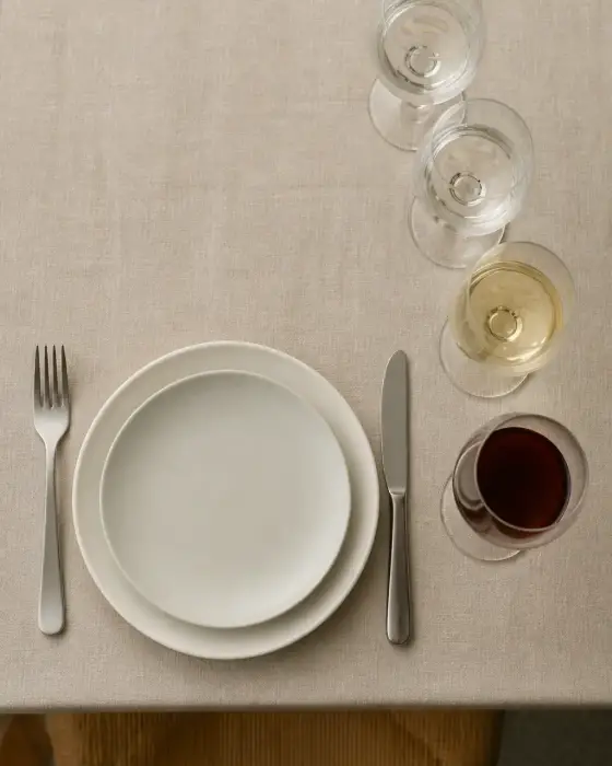 Table dressée vue de dessus avec assiette, couverts et quatre verres alignés en diagonale à droite de l’assiette