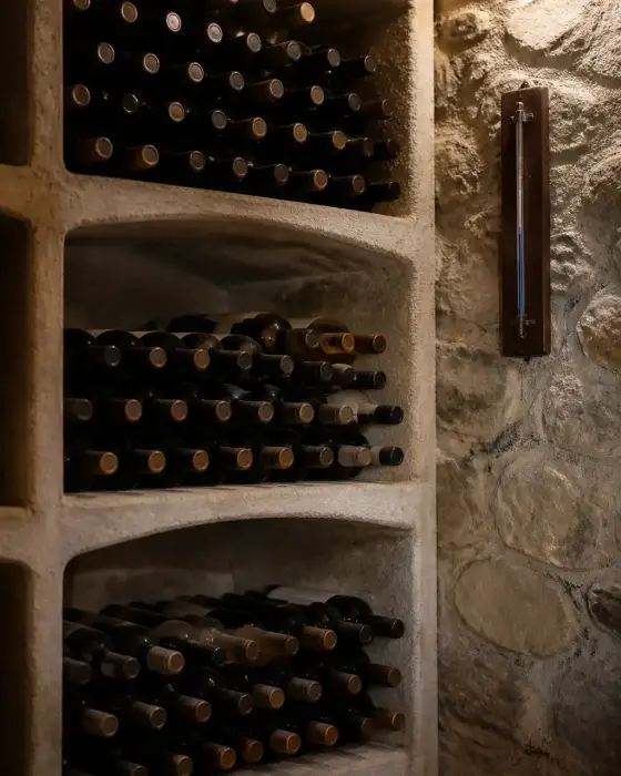 Casier à bouteilles dans une cave fraîche, bouteilles couchées, thermomètre mural affichant une température stable
